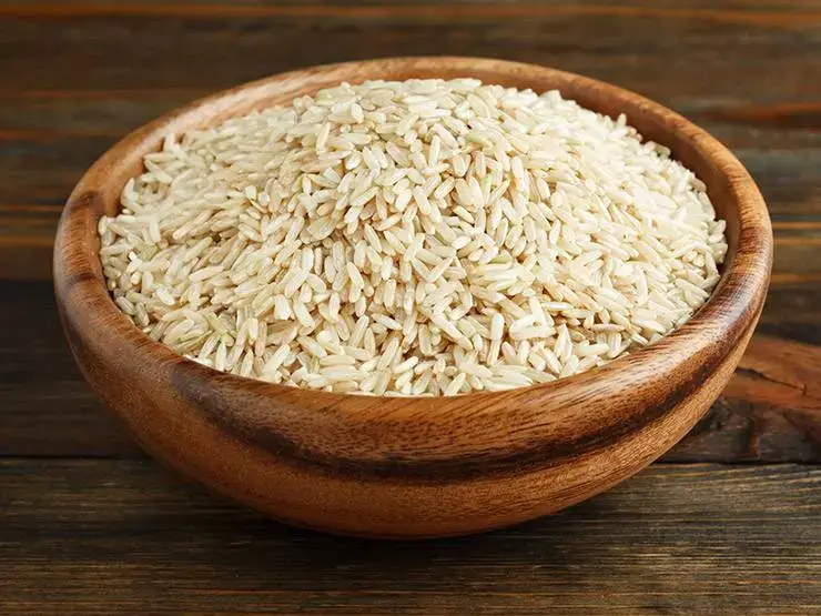 Uncooked brown rice on a wooden bowl