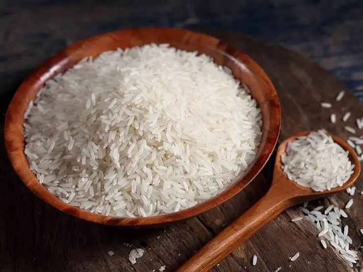 Uncooked white rice on a wooden bowl